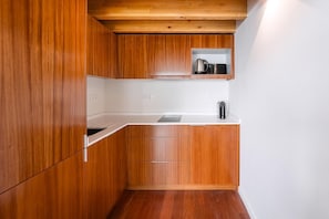 Une cuisine compacte avec des meubles en bois, un plan de travail blanc et une étagère intégrée.
