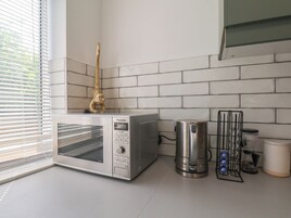 Una cocina equipada con microondas, cafetera y hervidor.