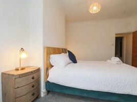 Un dormitorio con cabecera de madera, una mesita de noche con lámpara y una puerta a la derecha.