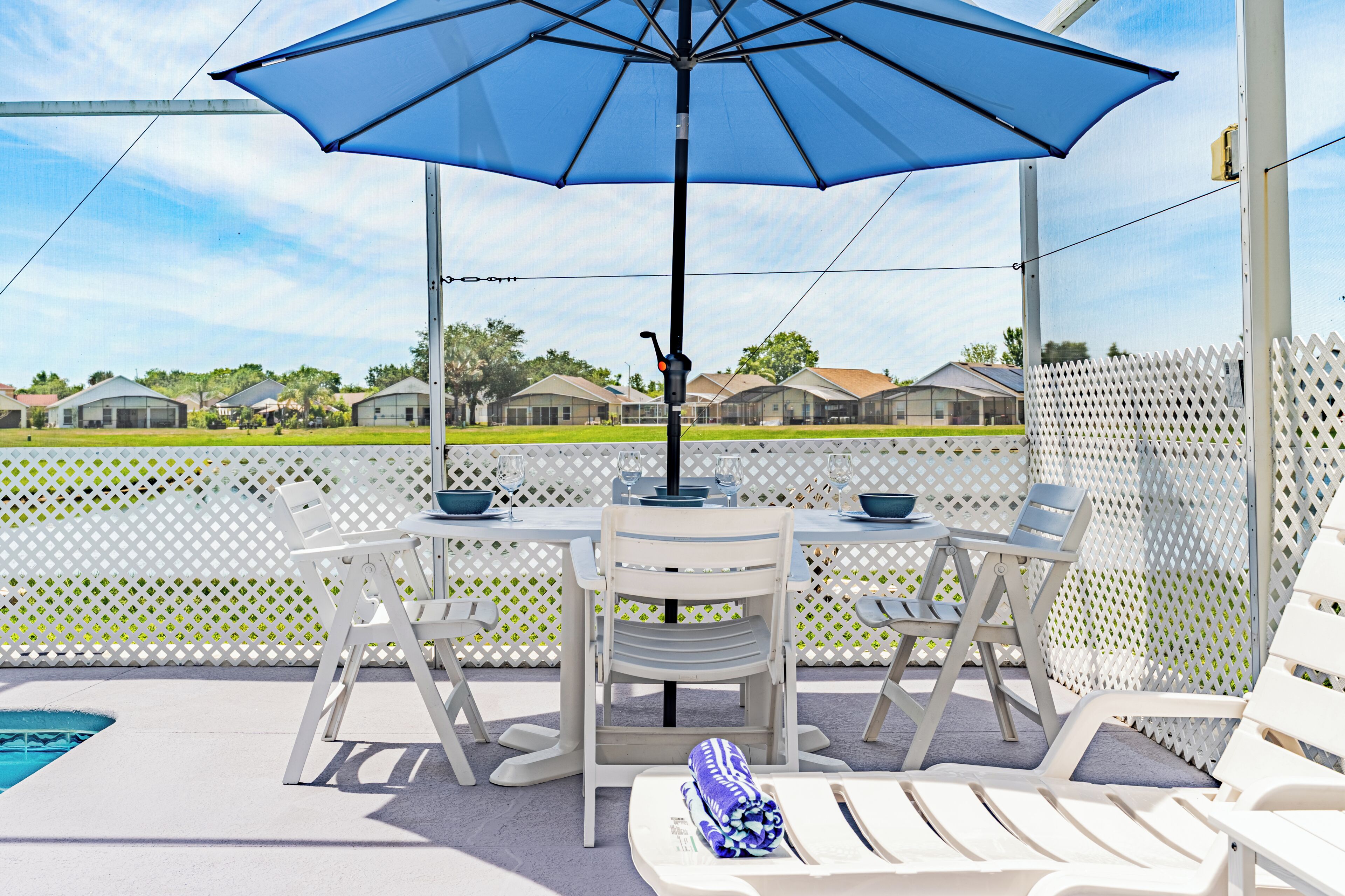 A covered outdoor seating area with a table, chairs, and an umbrella.