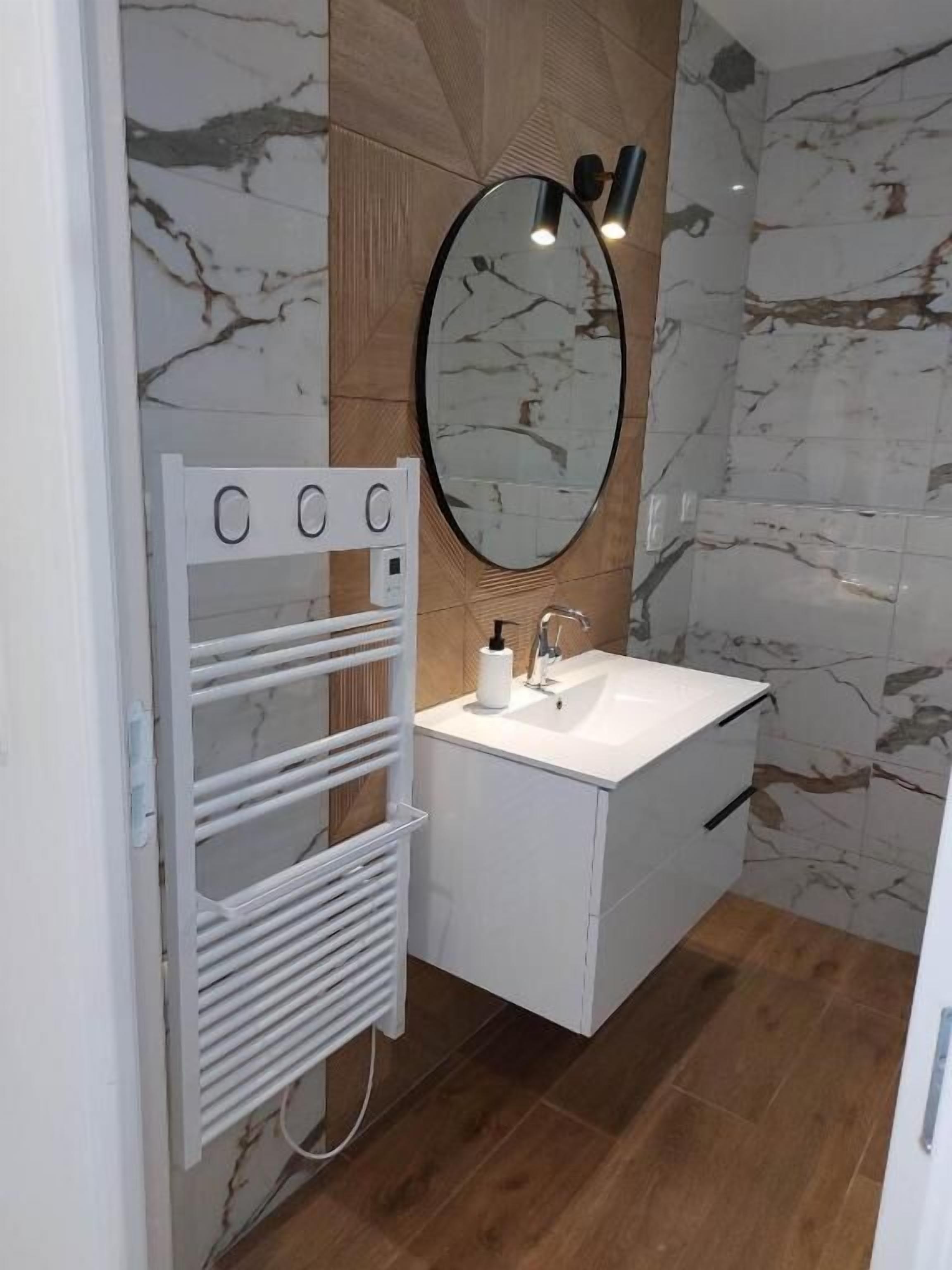 A bathroom with a white vanity, a mirror, a towel rack, and a shower.