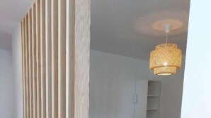 Une chambre à coucher avec un lit, une cloison en bois, un luminaire suspendu et une armoire blanche.