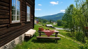 En stuga av trä med en bänk och ett picknickbord utanför.