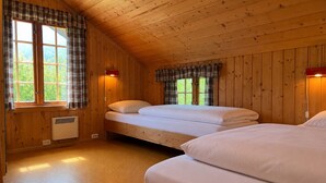 En stuga med träpanel, två sängar, ett fönster och en väggmonterad värmare.