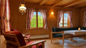 Un intérieur en bois avec un canapé, des fauteuils, une table et des rideaux.