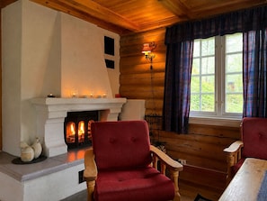 A cozy cabin interior with a fireplace, wooden walls, and plaid curtains.