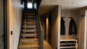A wooden staircase leading to a hallway with a bench and shoe rack. - New spacious mountain cabin with sauna, Geilo (Hol)