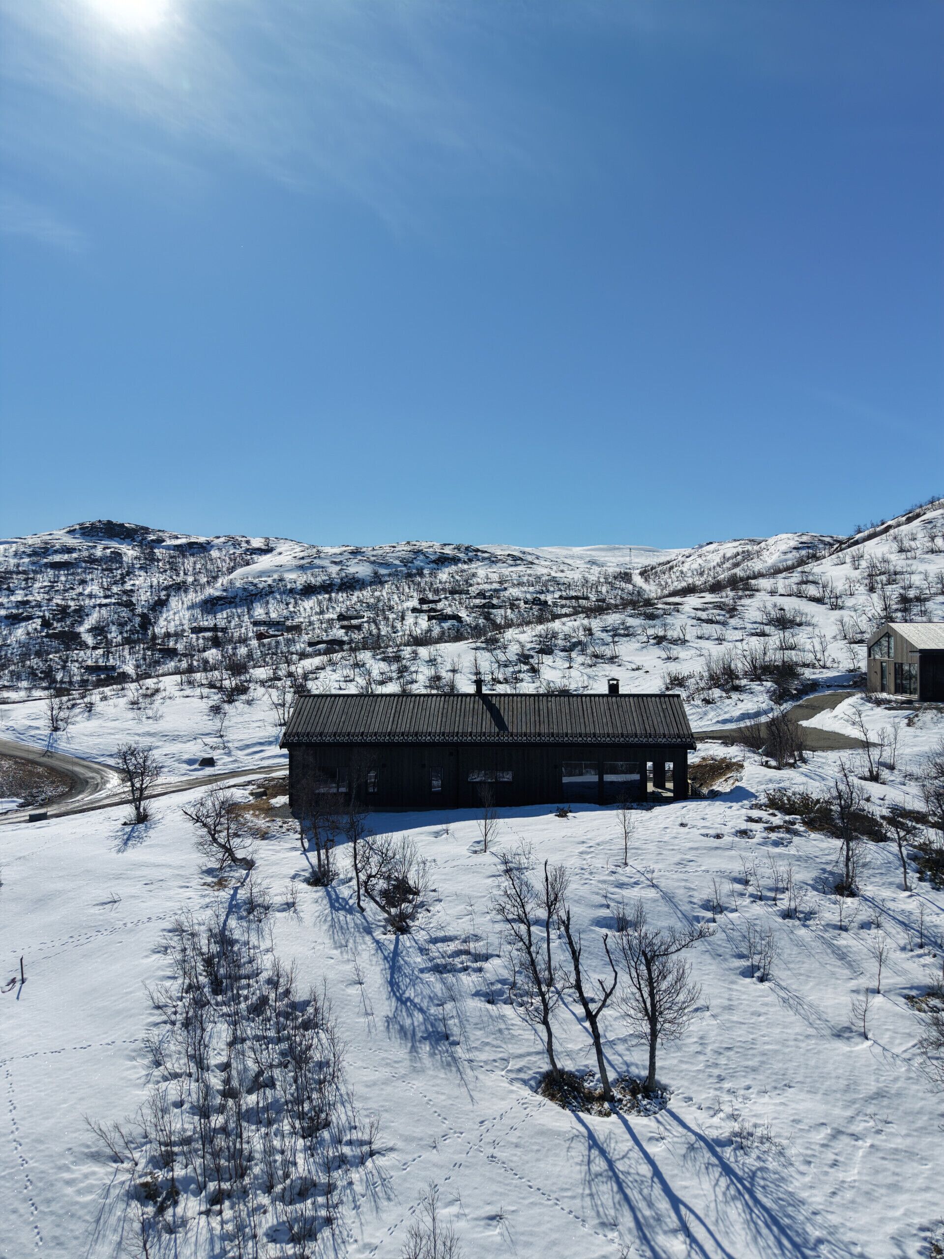 Paisaje nevado con un edificio que presenta un techo largo y oscuro y un frente plano.