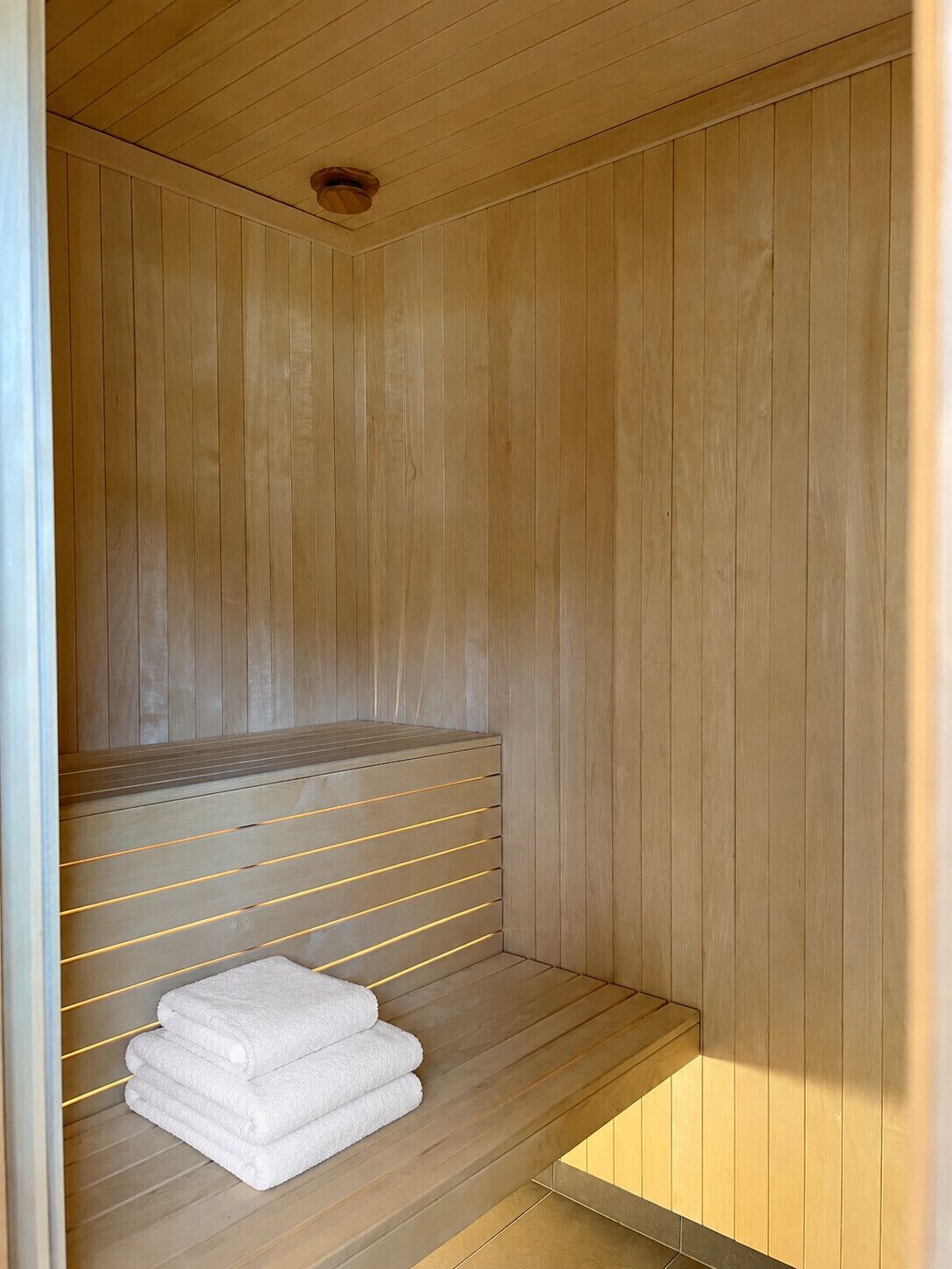 Eine Holzsauna mit einer Sitzbank und einem Ablagefach für Handtücher.
