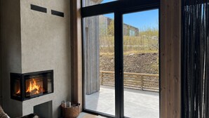 A modern interior with a fireplace, large windows, and a view of the outdoors. - New spacious mountain cabin with sauna, Geilo (Hol)