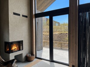 A modern interior with a fireplace, large windows, and a view of the outdoors.
