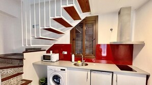 A compact kitchen with a washing machine, a microwave, and a red sink.