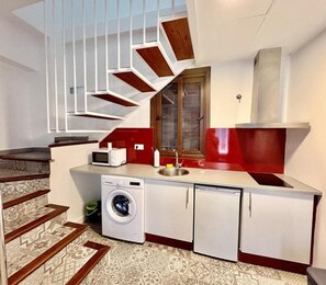 A compact kitchen with a washing machine, a microwave, and a red sink.