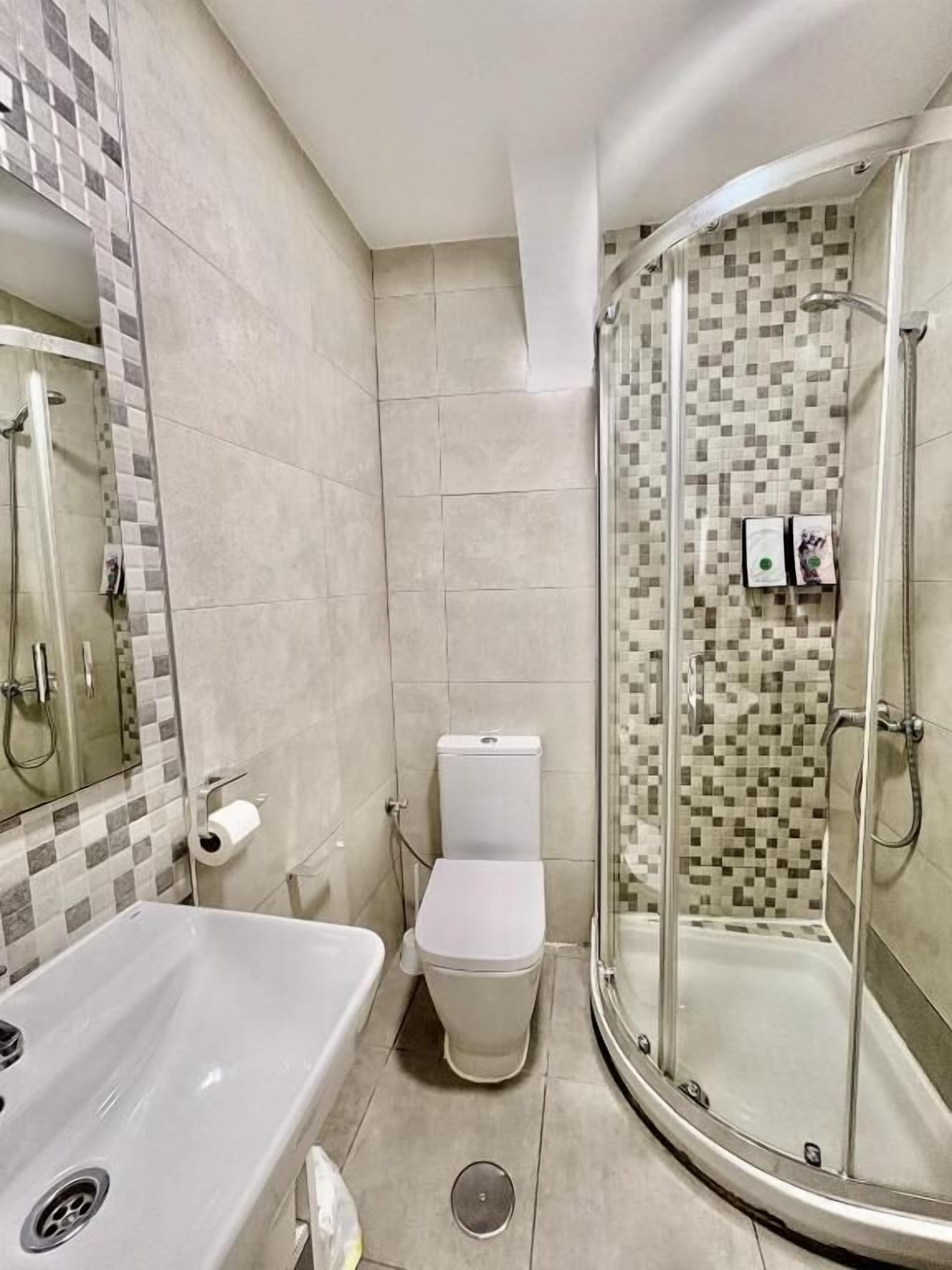 A bathroom with a shower, toilet, and sink.
