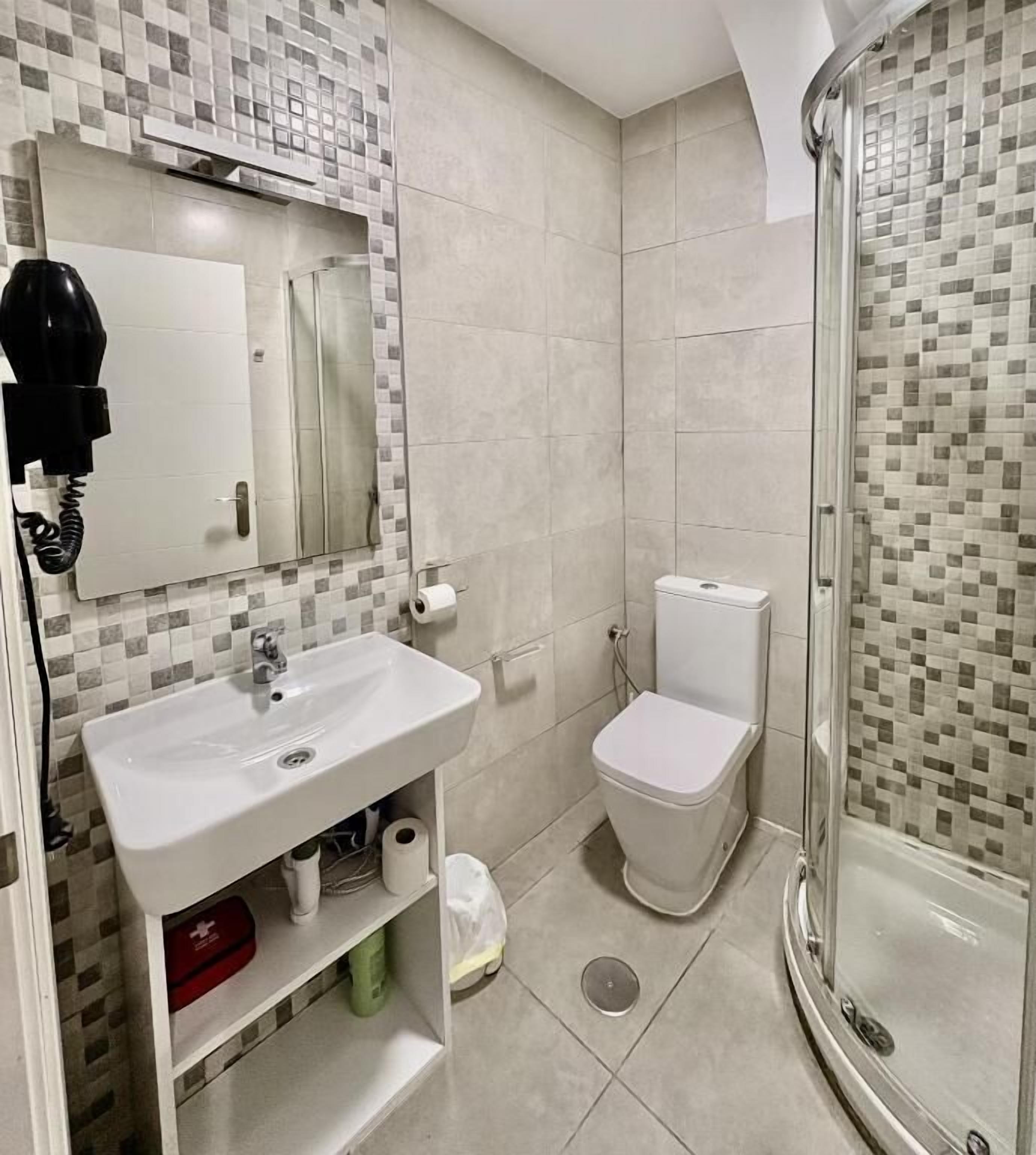 Une salle de bain avec un lavabo blanc, des toilettes et une douche à parois de verre.