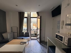 Ein Hotelzimmer mit Sofa, Stühlen, Esstisch, Mikrowelle, Fernseher und einem Balkon mit Aussicht.