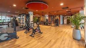 Una palestra con diverse attrezzature per l'allenamento, tra cui tapis roulant, macchinari per pesi e pesi liberi.
