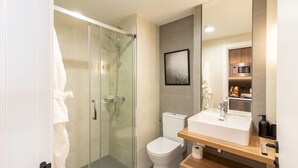 Un bagno moderno con cabina doccia in vetro, un water e un lavabo con piano in legno.