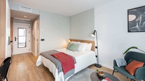 Una camera da letto moderna con un letto, una lampada da comodino e una sedia.