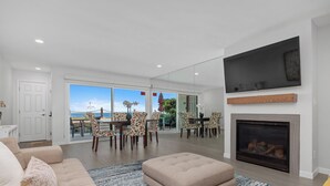 Una sala de estar con sofá, reposapiés, chimenea y un televisor grande.