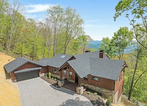 Eine Blockhütte mit Garage, einer überdachten Veranda und Blick auf ein bewaldetes Tal.