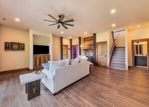Ein stilvolles Wohnzimmer mit Sofa, Fernseher, Deckenventilator und Holzböden.