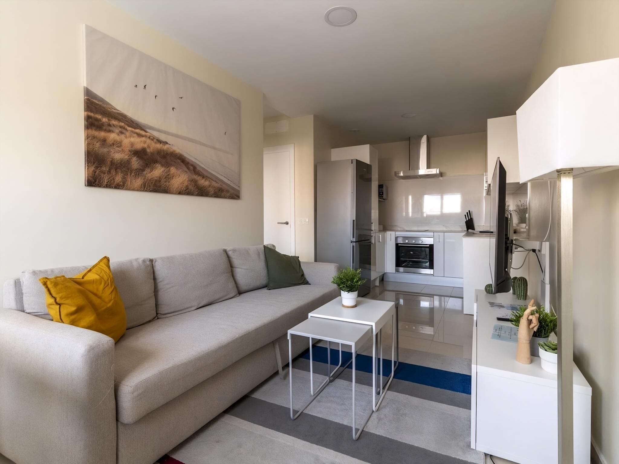 Ein modernes Wohnzimmer mit einer Couch, einem Couchtisch und einer Küche im Hintergrund.
