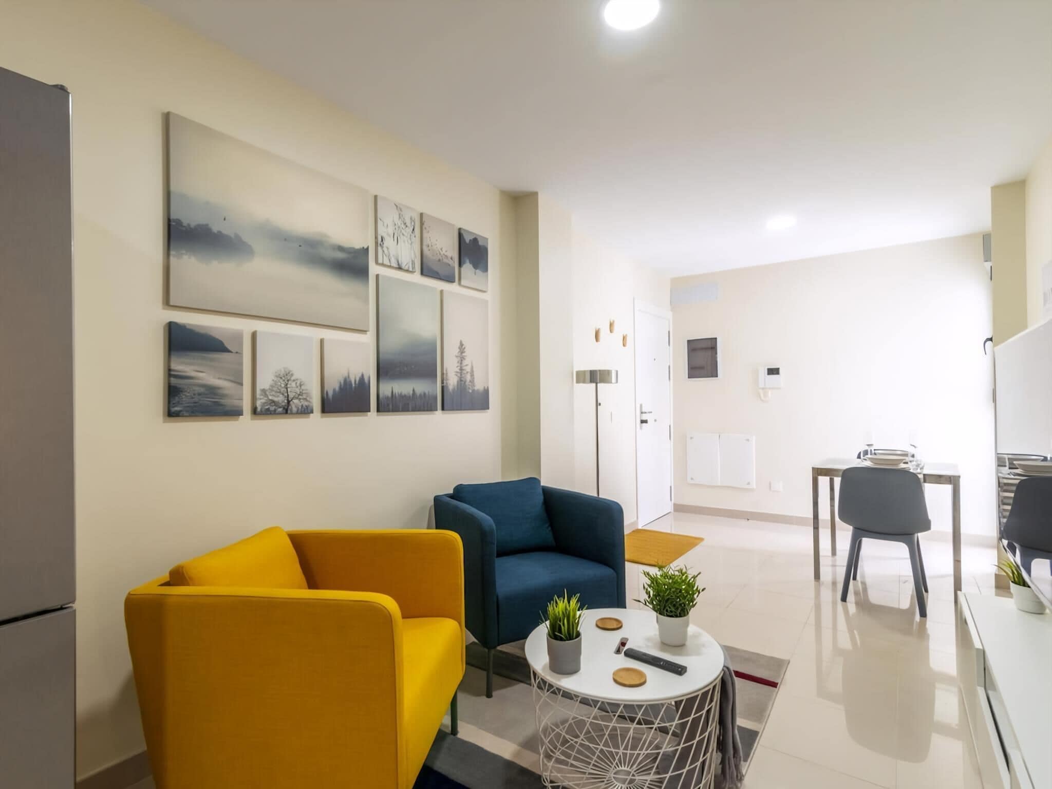 Ein modernes Wohnzimmer mit einer Couch, einem Sessel und einem kleinen runden Tisch mit einer Pflanze.