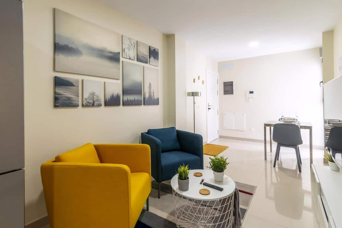 A modern living room with a sofa, armchair, and a small round table with a plant.
