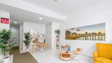 Un moderno vestíbulo de hotel con una recepción, área de descanso y un cuadro de gran formato con una vista de la ciudad.