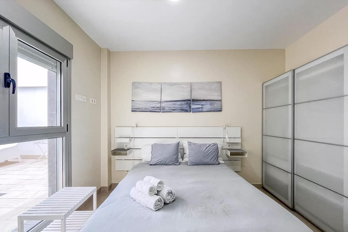 A modern bedroom with a bed, bedside tables, a window, and a view of the outdoors.