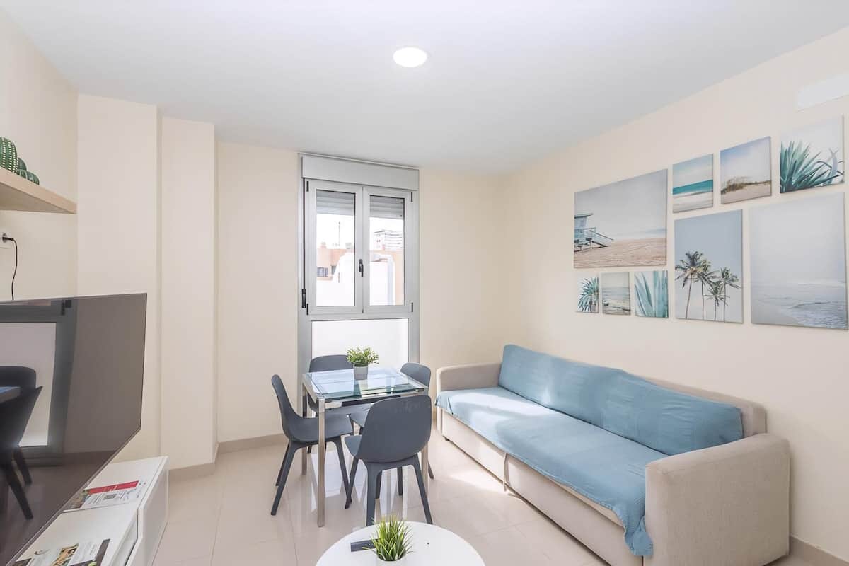 A compact living space with a glass dining table, a sofa, and a TV.