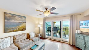 Ein Wohnzimmer mit einer Couch, einem Couchtisch, einem Fernseher und einem Deckenventilator.