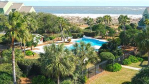Ein Pool, umgeben von Palmen, mit Blick auf das Meer.