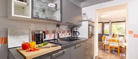 Une cuisine moderne équipée d’un évier, d’une machine à café et d’une planche à découper avec des légumes.