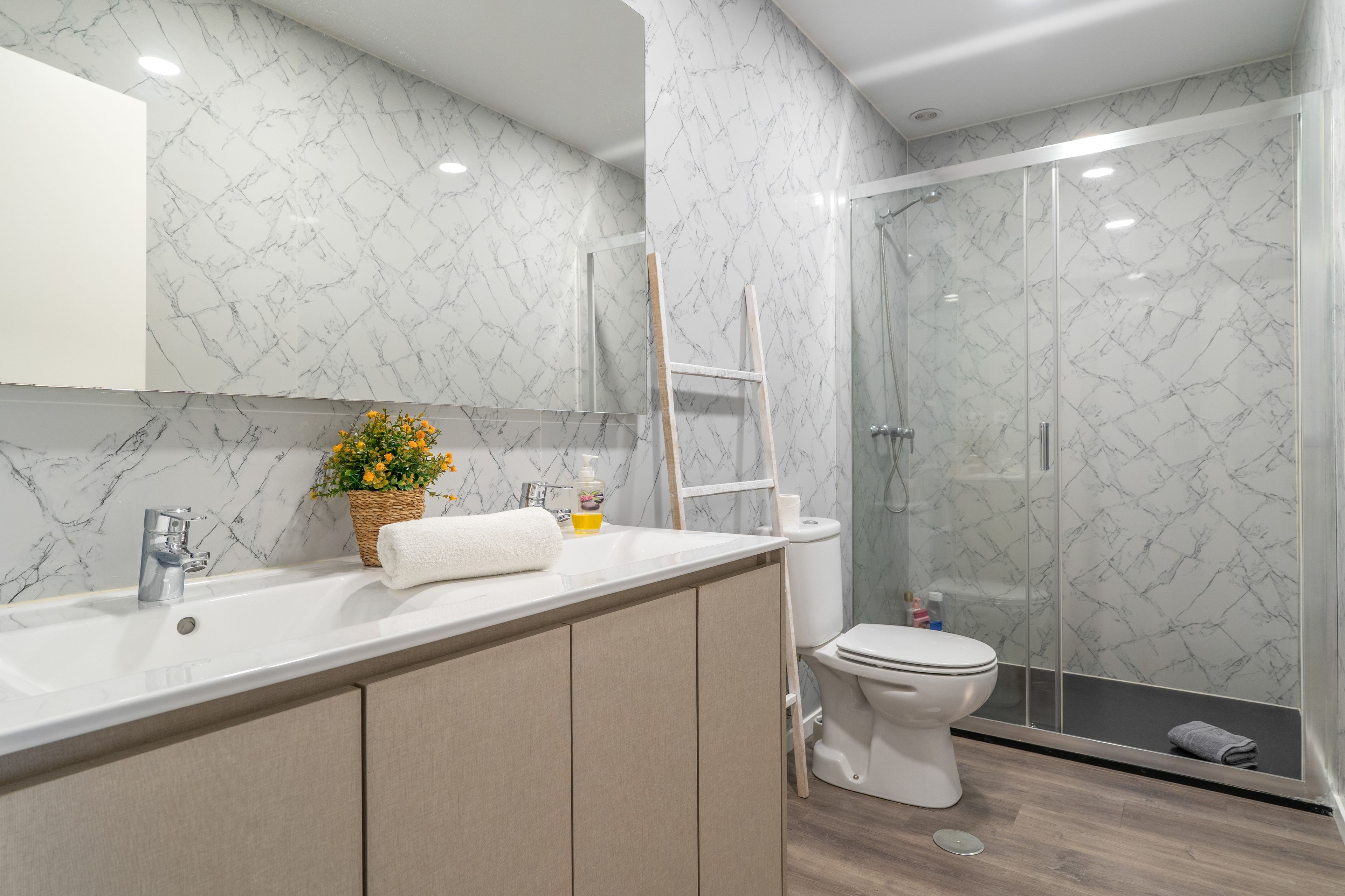 Une salle de bain moderne avec un pare-baignoire en marbre, une douche et un meuble-lavabo en bois.