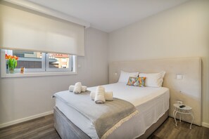 Habitación de hotel con cama, una mesita, una ventana con vistas y una mesita de noche con lámpara.