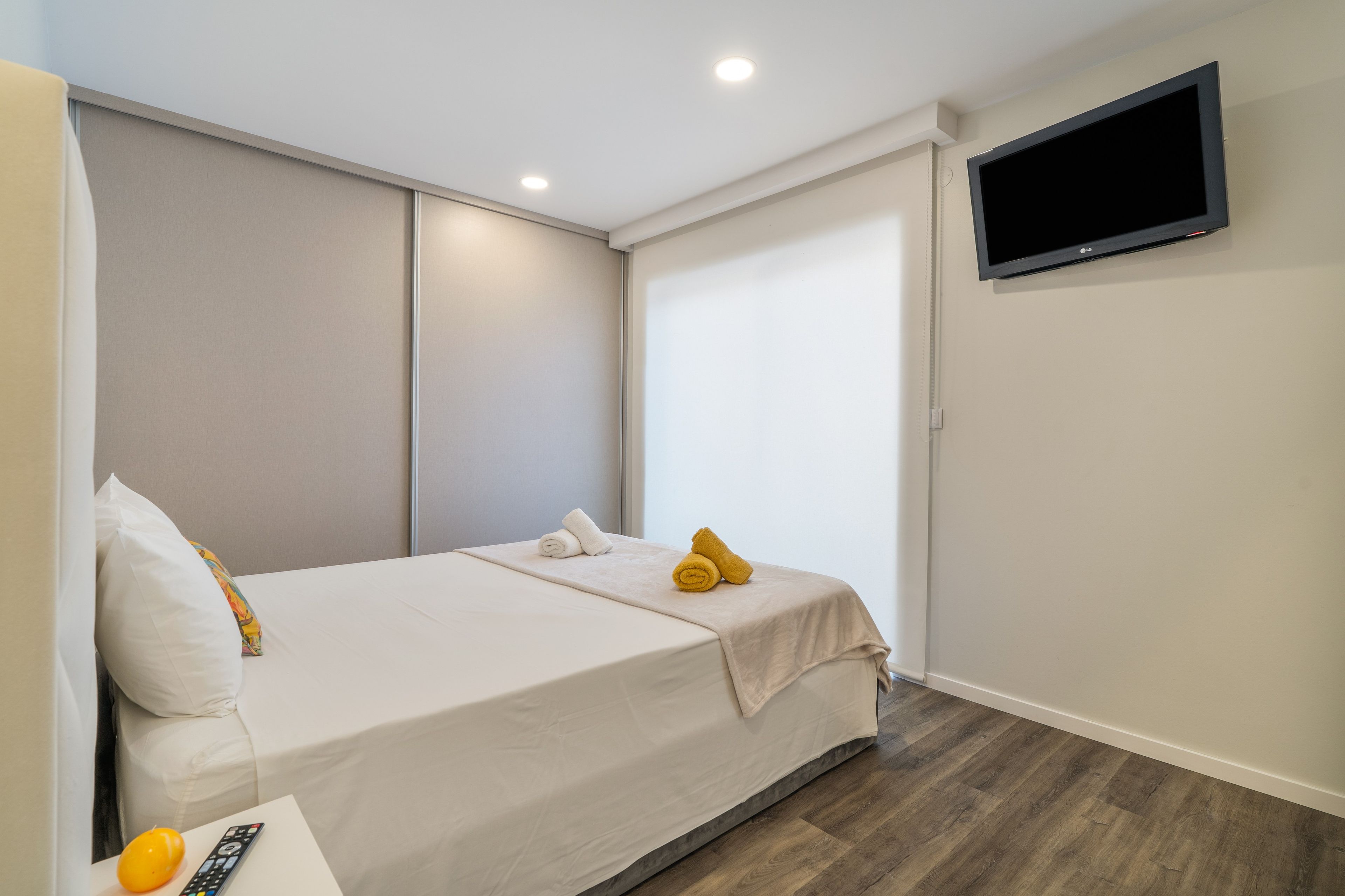 Une chambre d’hôtel avec un lit, un téléviseur fixé au mur et un plancher en bois.