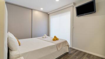Une chambre d’hôtel avec un lit, un téléviseur fixé au mur et un plancher en bois.
