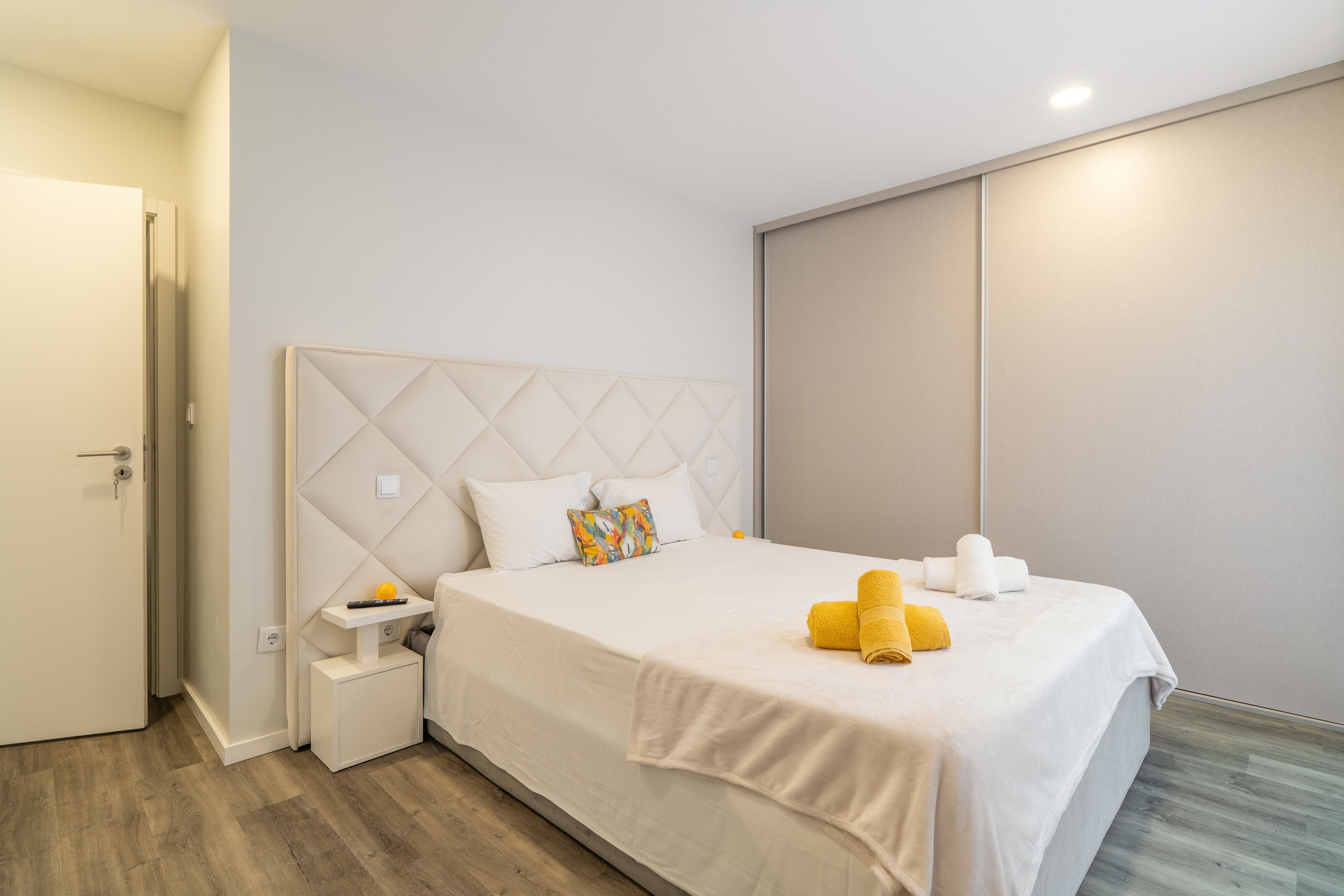 Een hotelkamer met een bed, nachtkastje en een deur.