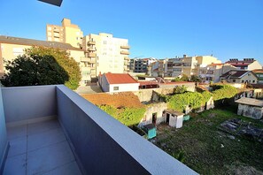 Zona residencial com vários edifícios de apartamentos, um pequeno jardim e varandas visíveis.