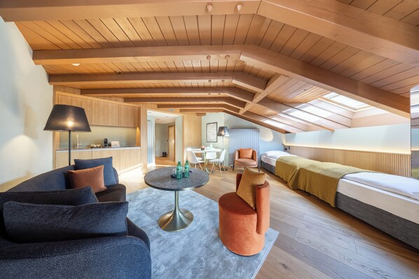 Habitación tipo loft con techo alto, comedor y una zona de estar acogedora con sofá y reposapiés.