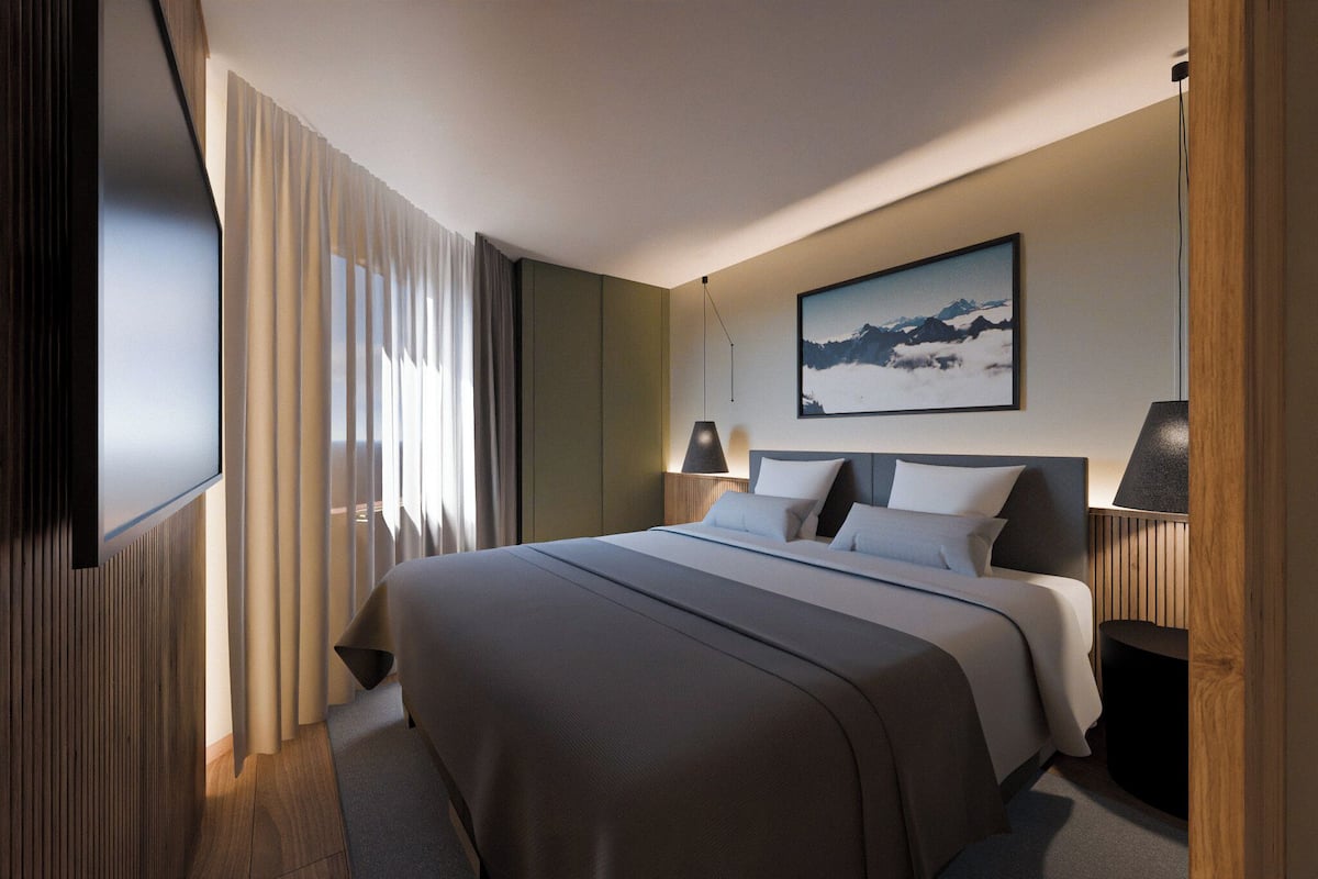 Habitación de hotel moderna con una cama grande, televisión de pantalla plana, un cuadro en la pared y una ventana con cortinas.