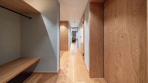 Un pasillo con suelo de madera, un banco y una puerta a la derecha.