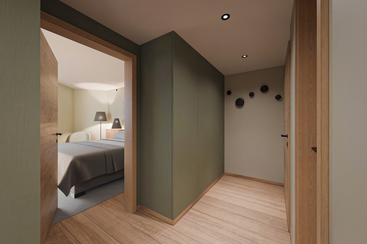 Un dormitorio con cama, mesita de noche, lámpara y vista a otra habitación.