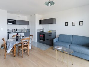 Eine moderne Küche mit Essbereich, einem blauen Sofa und einem kleinen Beistelltisch.