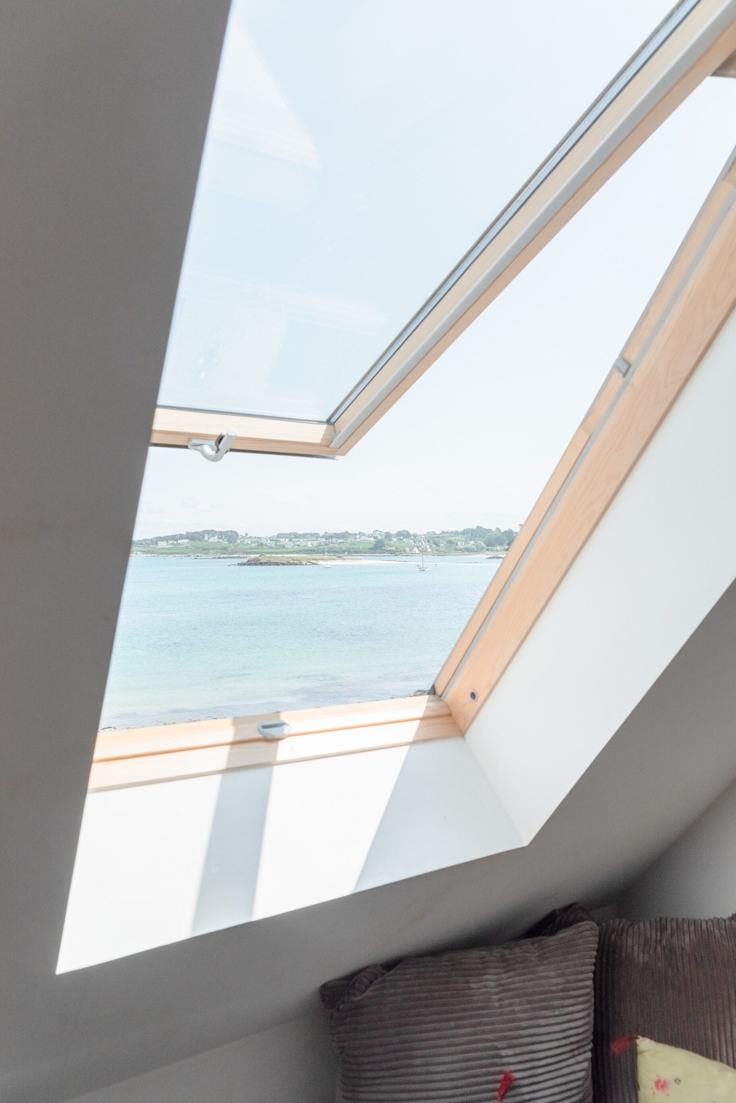 A skylight in a room with a view of a body of water and a distant shoreline.
