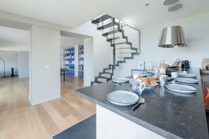 A modern kitchen with a central island, a staircase, and a dining area. - Plouguerneau House Near Lighthouse (Plouguerneau)