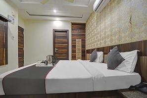 A hotel room with a bed, bedside table, and a wall-mounted air conditioning unit. - Townhouse Oak Iskcon Jaipur Formerly Olive Greens (Jaipur)