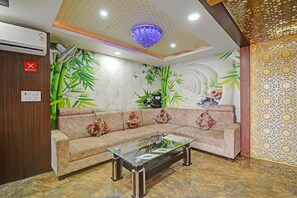 A reception area with a sofa, a glass coffee table, and a decorative ceiling. - Deluxe Olive Greens (Jaipur)